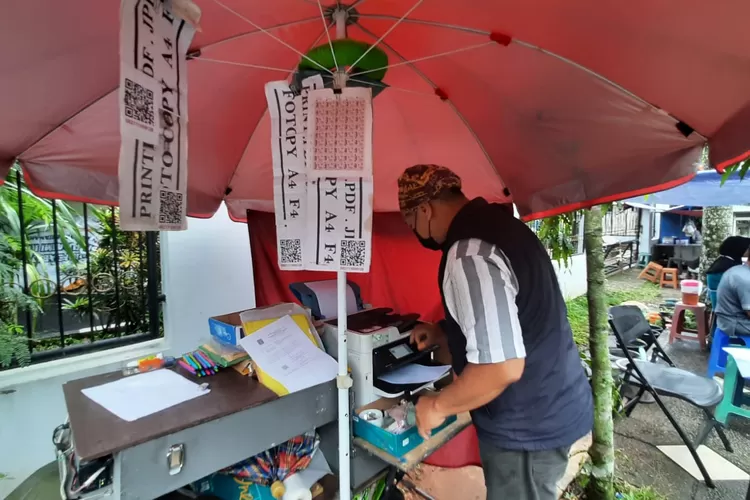 Layani: pemilik fotokopi keliling, Ade Yofi sedang melayani pelanggan di Boulevard, Kota Kembang, Kecamatan Cilodong, Kota Depok, Kamis (17/11). ASHLEY/RADARDEPOK