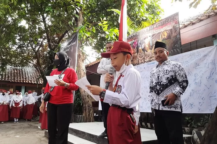 HARI GURU : Seorang siswa SDN Pondok Cina 1 membacakan puisi selepas upacara peringati hari guru nasional tanpa kehadiran guru di Jalan Stasiun Pondok Cina, Kelurahan Kemirimuka, Kecamatan Beji, Kota Depok, Jumat (25/11). ASHLEY/RADAR DEPOK