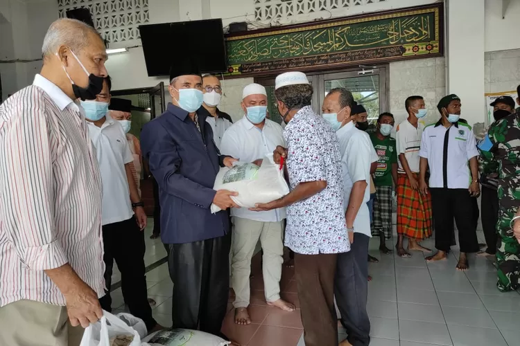 BAGIKAN: Ketua BKM Agung Medan, Impun Siregar didampingi sejumlah pengurus seperti H Yuslin Siregar, Hendra DS dan lainnya bagikan bantuan sembako secara simbolis kepada pelaku UMKM di sekitaran masjid tersebut, Kamis (19/8) sore.