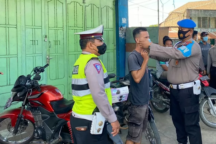 Petugas memberi dan memasangkan Masker kepada warga yang kedapatan tidak memakai Masker. (Photo :Realitasonline.id/H.Guntur Sinaga)