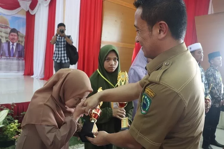 Foto: Sekdakab Paluta Patuan Rahmat P Syukurmemberikan hadiah kepada salah satu pemenang Festival Seni Qasidah ke III tingkat Kabupaten Paluta, Selasa (23/08). (Realitasonline.id/ ASR)