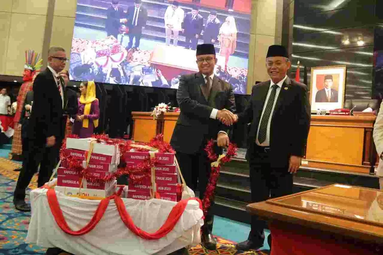 Gubernur DKi Jakarta Anies Baswedan menerima berkas RAPBD DKI 2020 dari Ketua DPRD DKi Prasetio Edi Marsudi pada rapat paripurna, Rabu (11/12/2019).