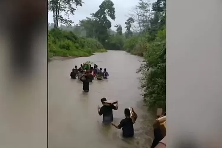 Iringan jenazah warga Pekon, Desa Pemerihan, Kecamatan Bangkunat, Kabupaten Pesisir Barat, Lampung, yang menyeberangi sebuah sungai untuk sampai ke TPU.