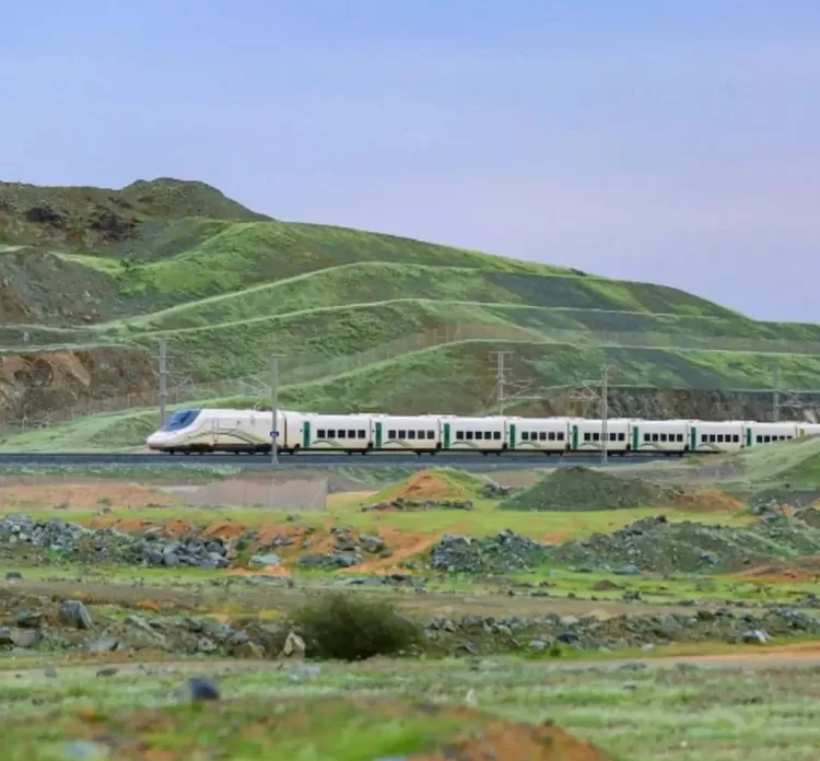 Sebuah kereta cepat di Arab Saudi melintas di tengah pegunungan yang menghijau.