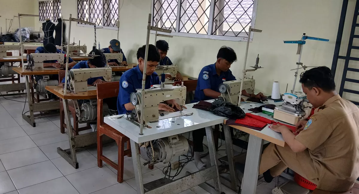 Guru dan siswa SMKN 3 Bondowoso sedang praktek menjahit untuk kebutuhan jok mobil. (SketsaNusantara.id)